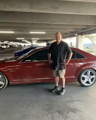 Benjamin Hornung standing beside a red Mercedes in a parking garage